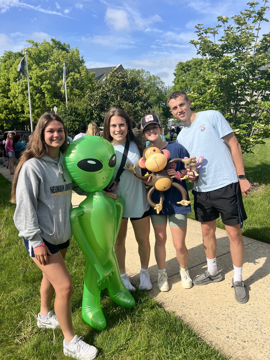 Four students posing with an inflatable alien and monkey