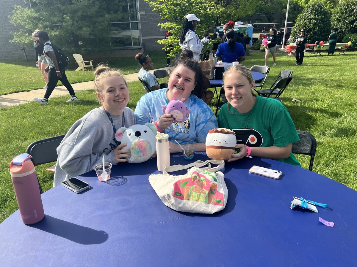 Three students posing with stuffed animals at table