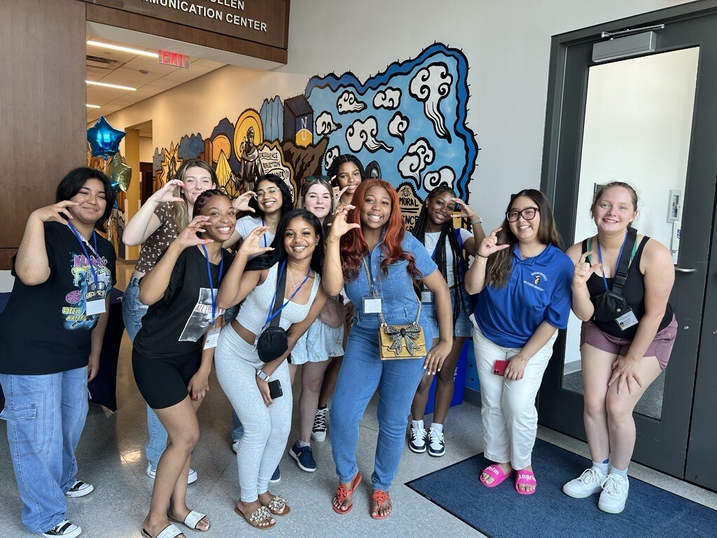 New students standing with their Orientation Leader holding up the letter 'C' to reflect the group.